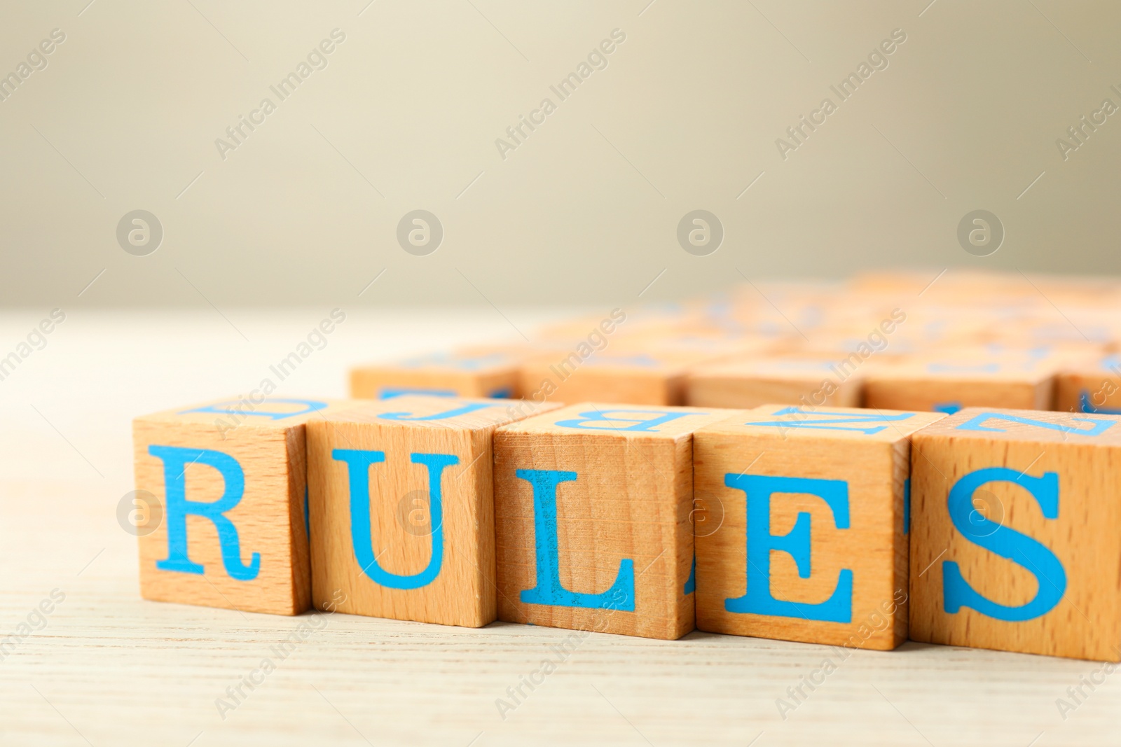 Photo of Word Rules made of cubes with letters on light wooden table, closeup