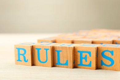 Photo of Word Rules made of cubes with letters on light wooden table, closeup
