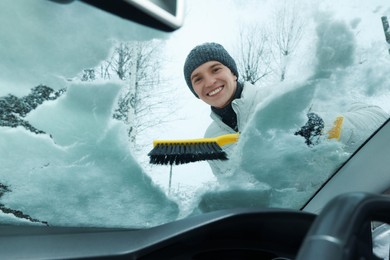 Photo of Man cleaning snow from car windshield, view from inside