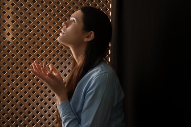 Photo of Woman praying to God during confession in booth