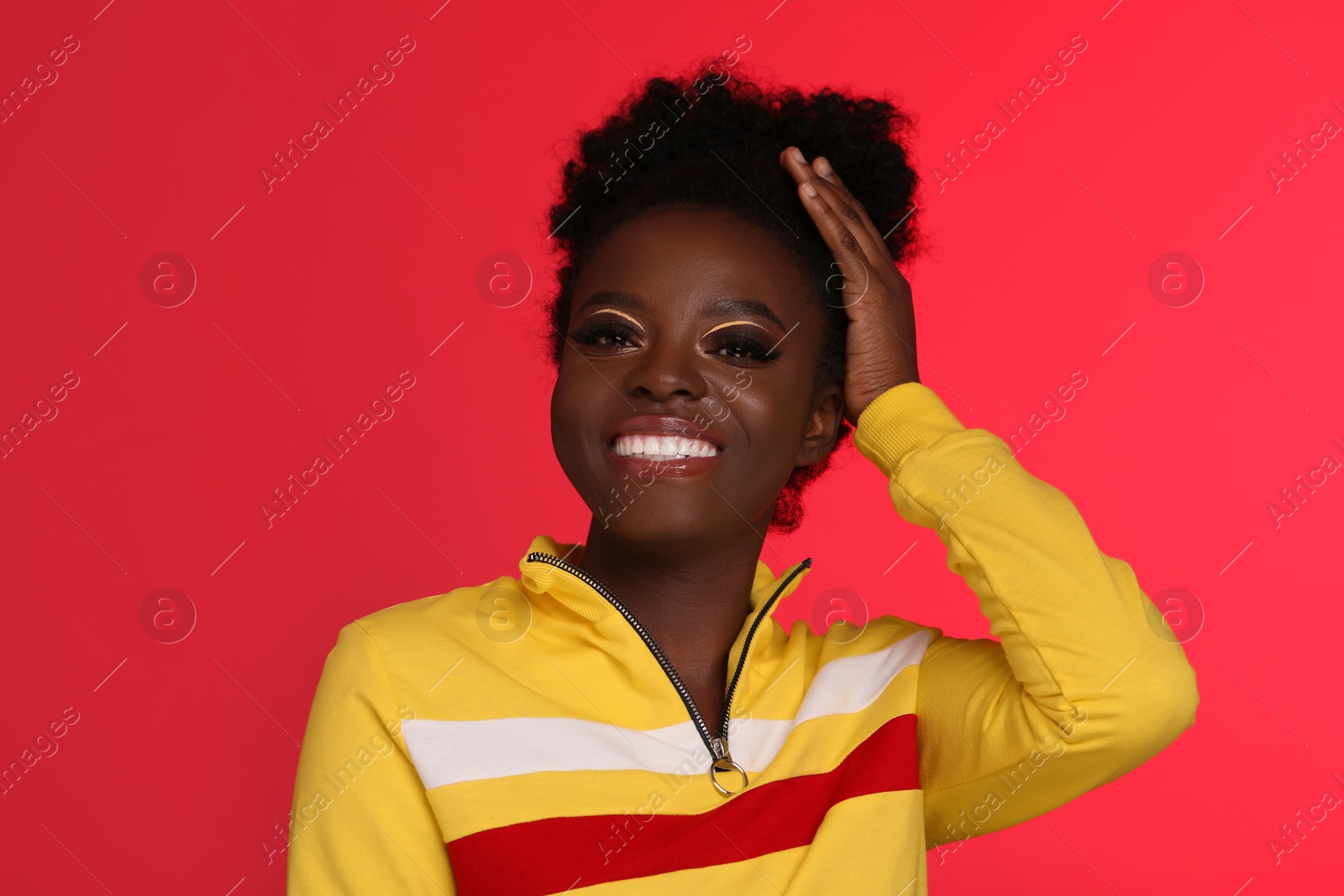 Photo of Fashionable portrait of beautiful happy woman with bright makeup on coral background