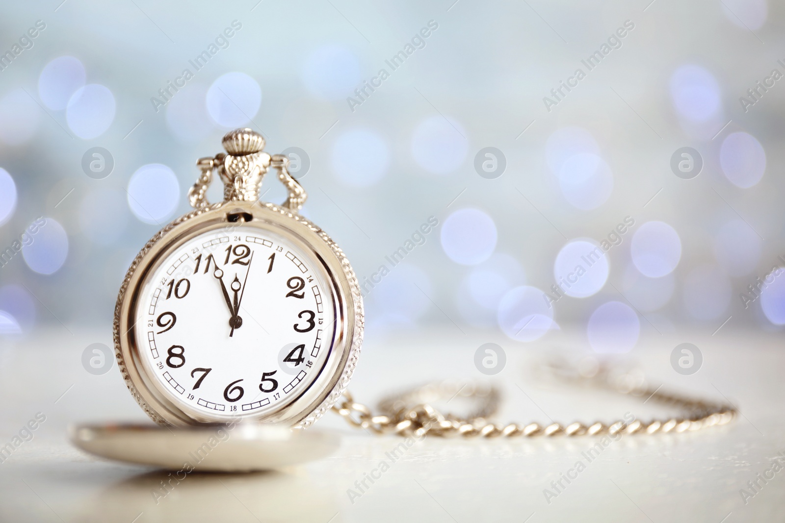 Photo of Pocket watch on table against blurred lights, space for text. New Year countdown