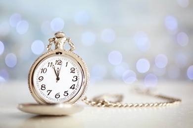 Photo of Pocket watch on table against blurred lights, space for text. New Year countdown