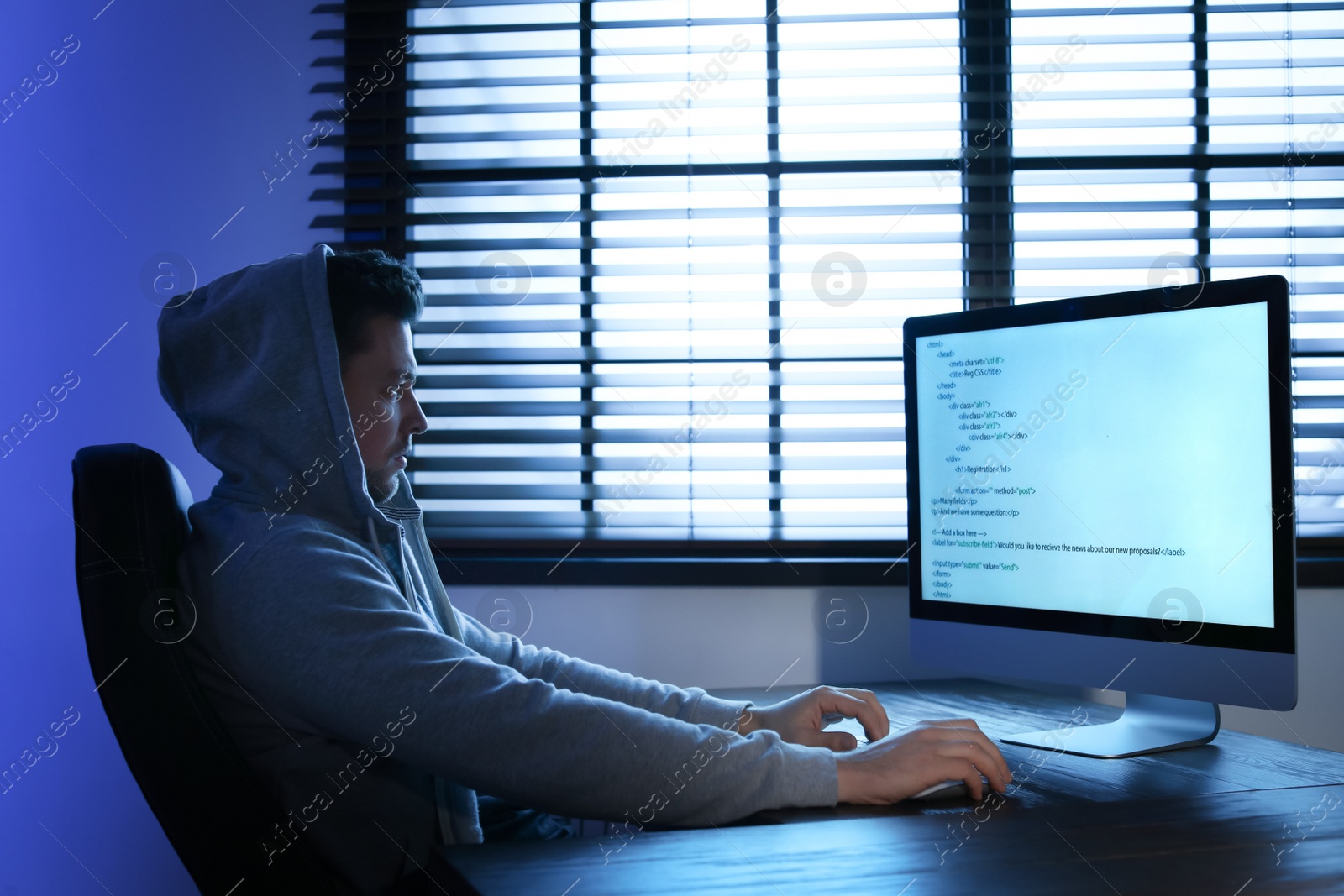 Photo of Man using computer in dark room. Criminal offence