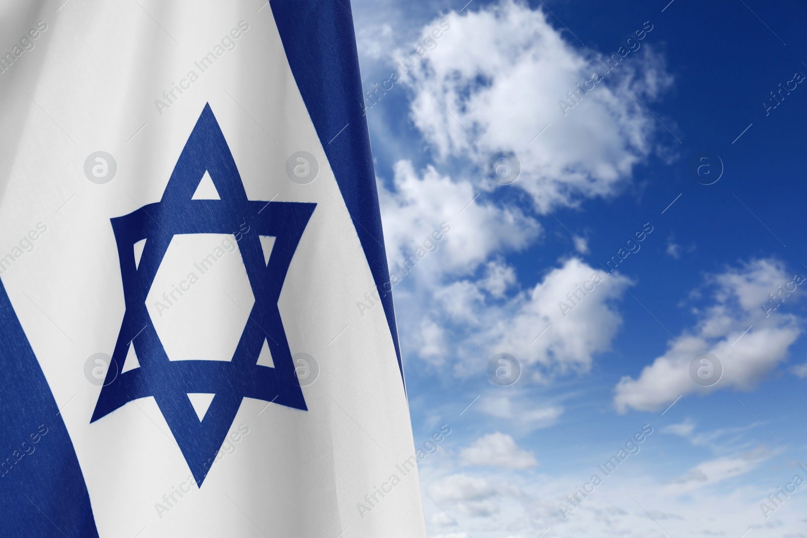 Image of National flag of Israel against blue sky with clouds