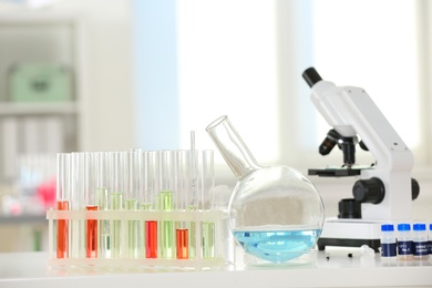 Photo of Laboratory glassware and microscope on table indoors. Research and analysis