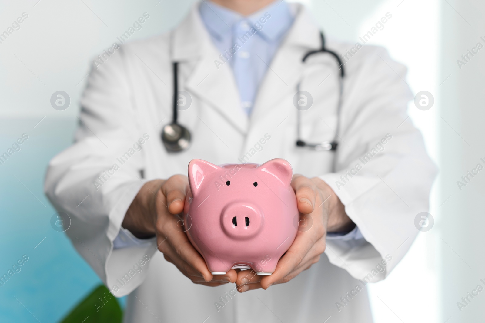 Photo of Doctor with piggy bank in hospital, closeup