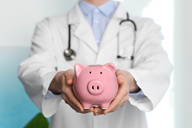 Photo of Doctor with piggy bank in hospital, closeup
