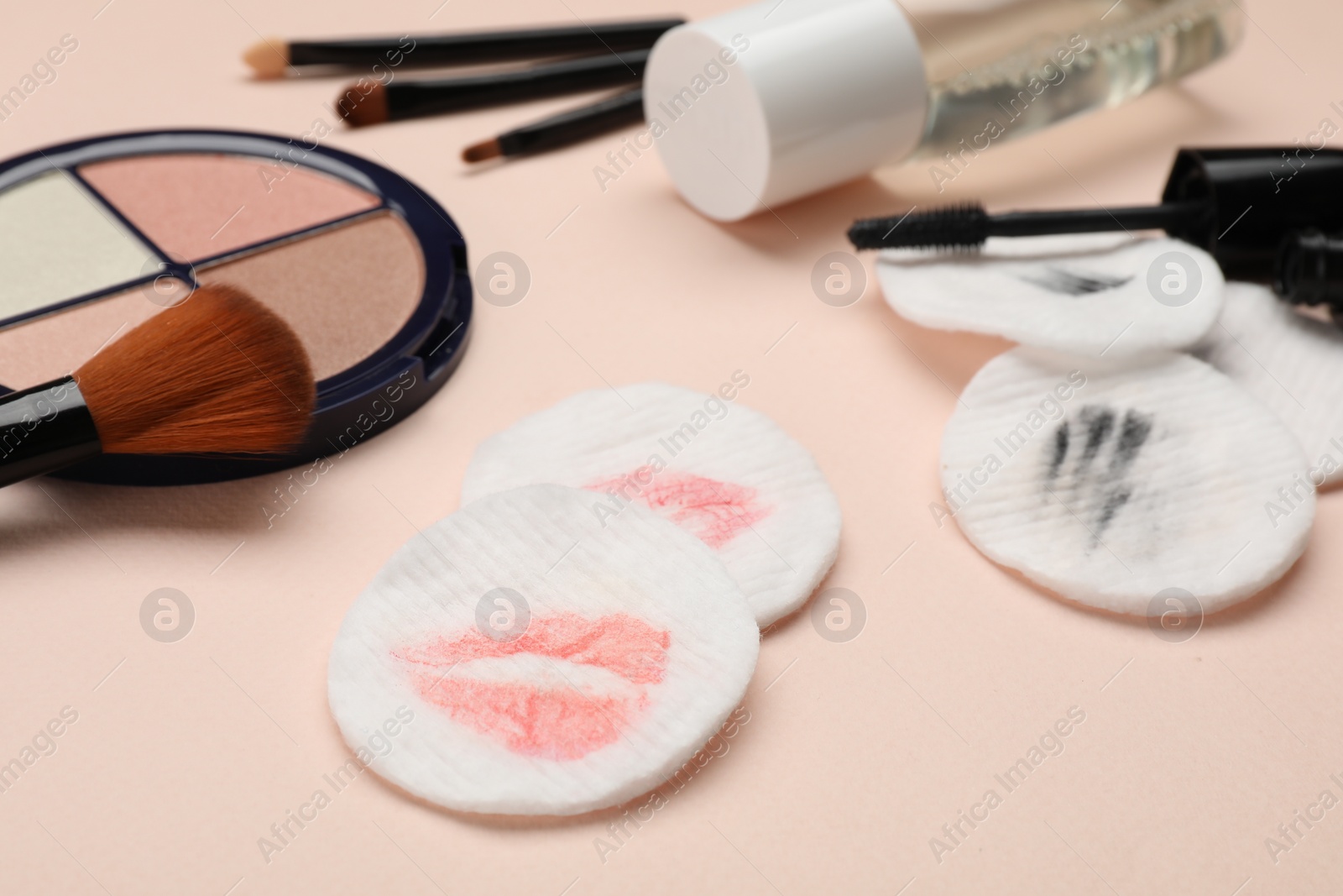 Photo of Dirty cotton pads after removing makeup and cosmetic products on beige background, closeup