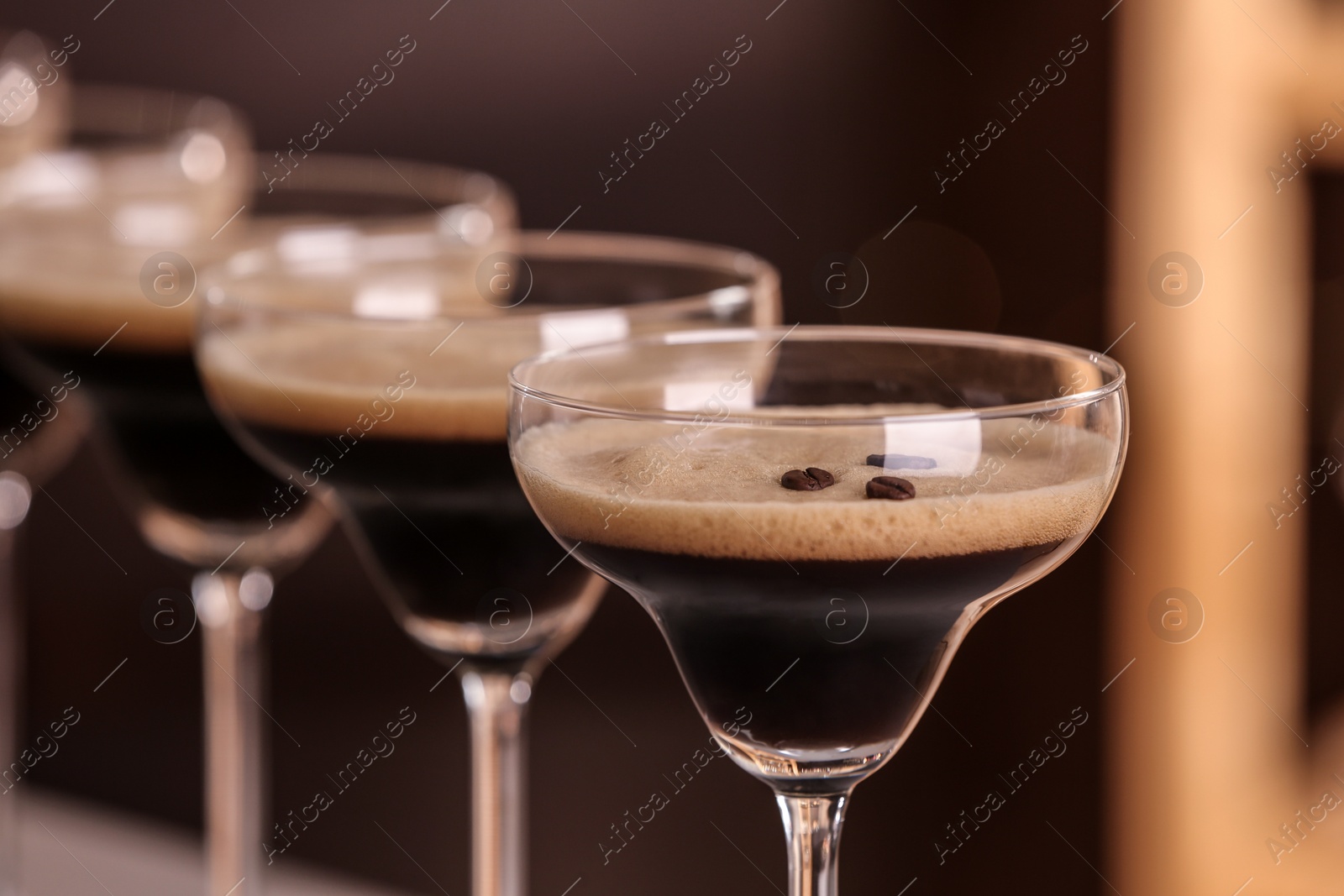 Photo of Glasses of delicious Espresso Martini on blurred background. Alcohol cocktail