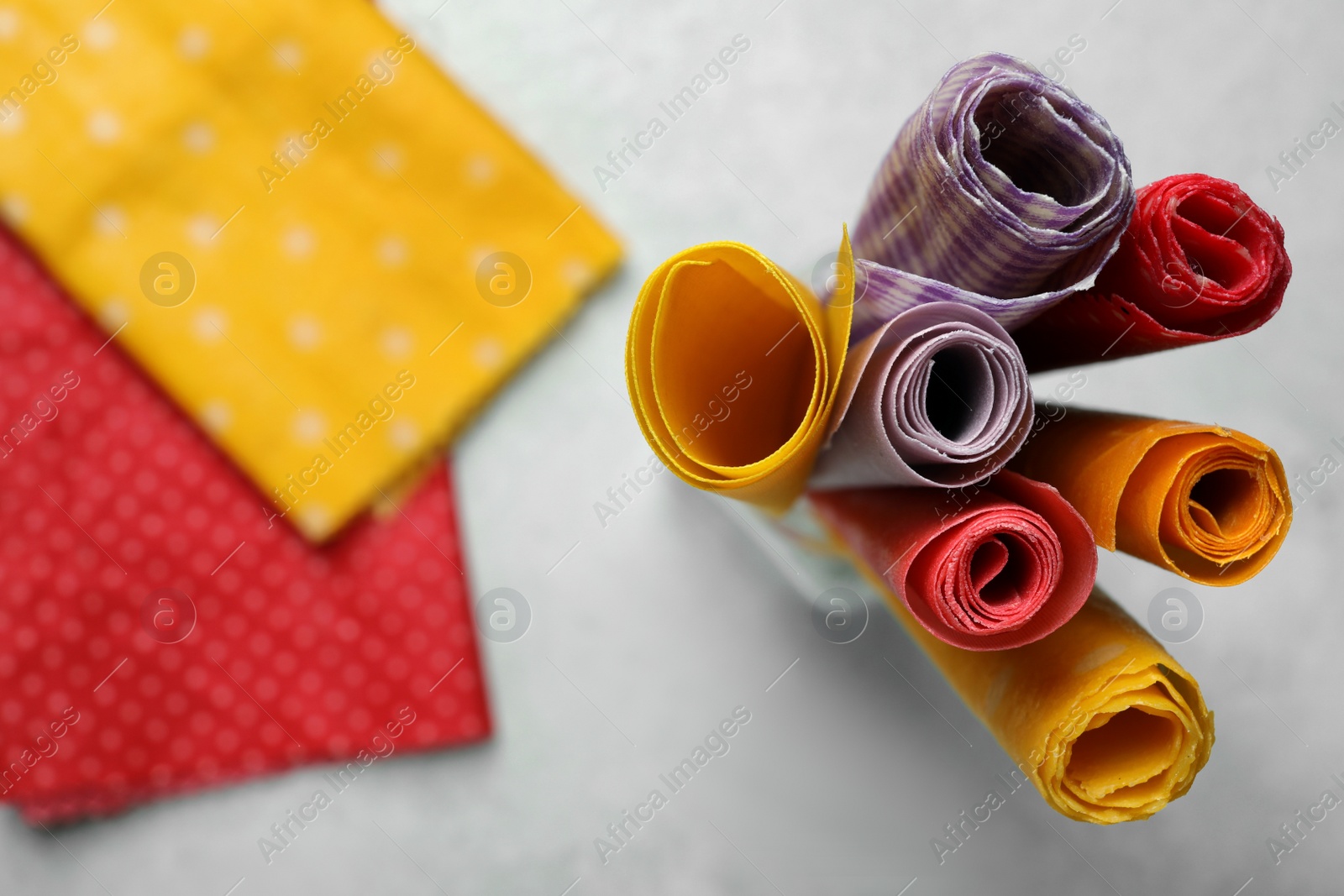 Photo of Colorful beeswax food wraps on light table, top view. Space for text