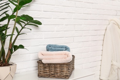 Basket with clean folded towels on table near brick wall. Space for text