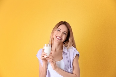 Beautiful young woman drinking milk on color background