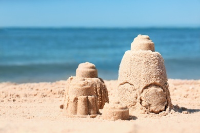 Photo of Sand figures on beach near sea. Space for text