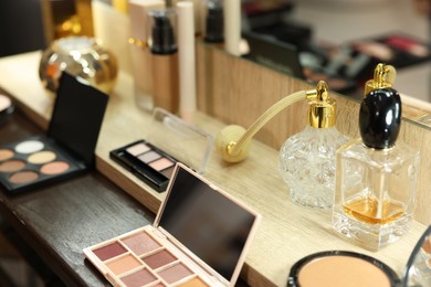 Makeup room. Cosmetic products and perfumes on wooden dressing table indoors