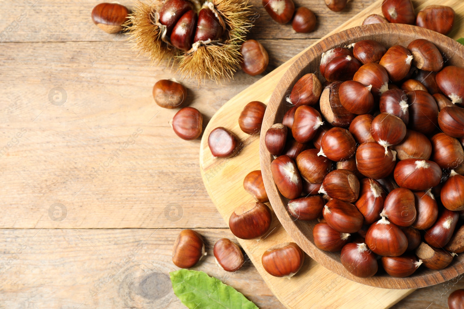 Photo of Fresh sweet edible chestnuts on wooden table, flat lay. Space for text