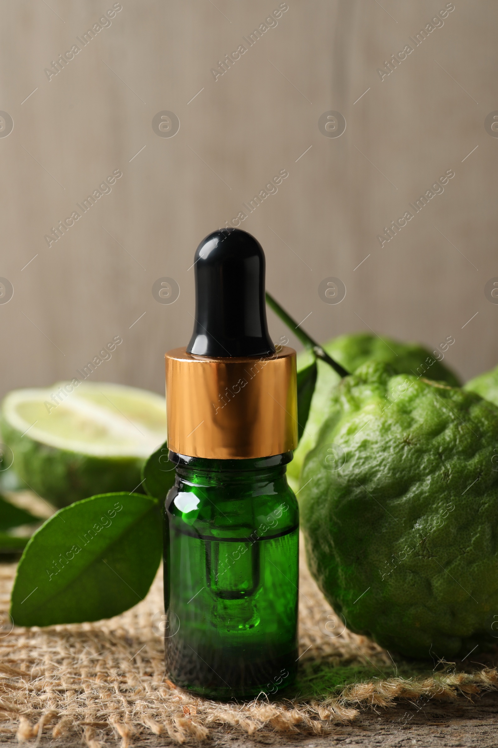 Photo of Bottle of essential oil and fresh bergamot fruits on table