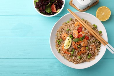 Photo of Tasty rice with shrimps and vegetables served on turquoise wooden table, flat lay. Space for text