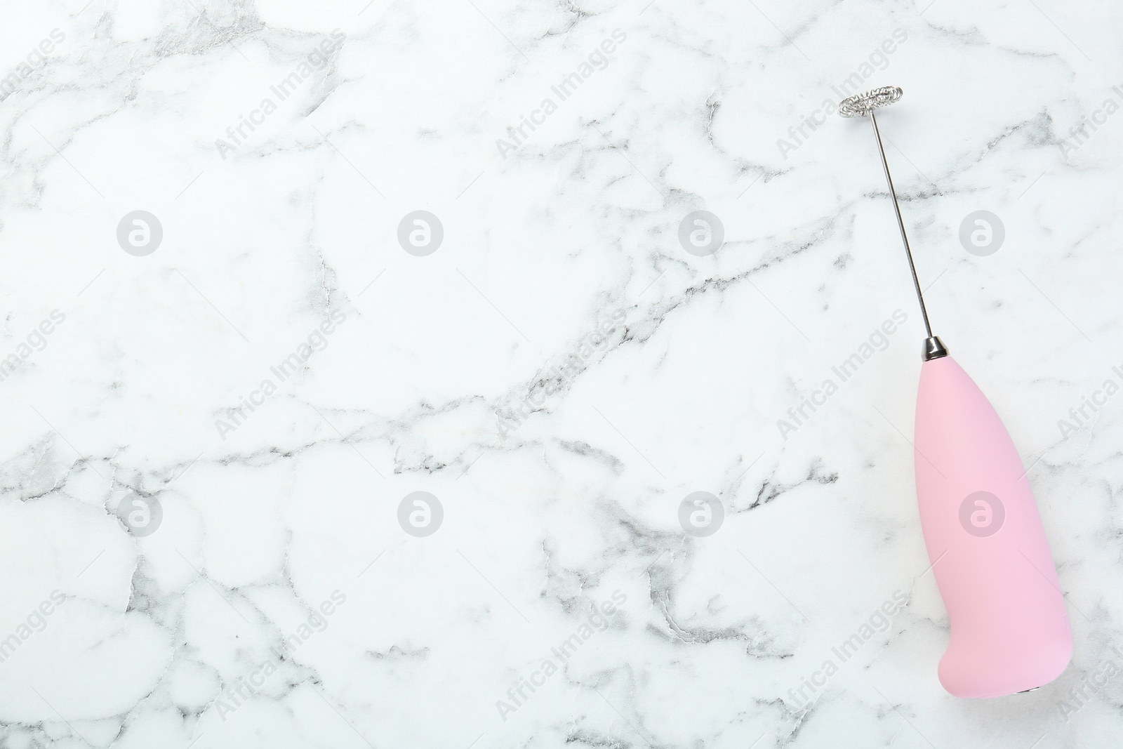 Photo of Pink milk frother wand on white marble table, top view. Space for text