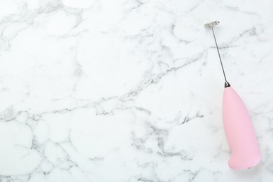 Photo of Pink milk frother wand on white marble table, top view. Space for text