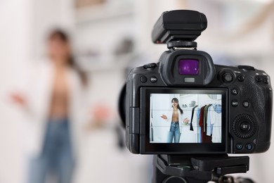 Fashion blogger showing her clothes while recording video at home, focus on camera