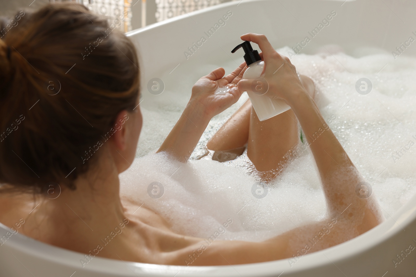 Photo of Beautiful woman pouring shower gel onto hand in bath indoors, focus on hands