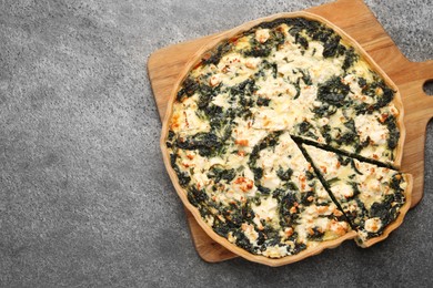 Delicious homemade spinach quiche on gray table, top view. Space for text