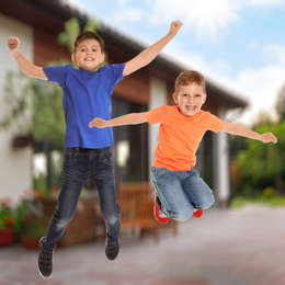 Image of Happy boys jumping near house. School holidays