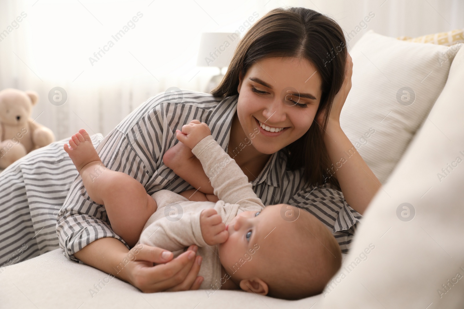 Photo of Young woman with her little baby on sofa at home