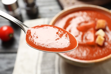 Spoon with fresh homemade tomato soup on blurred background, closeup