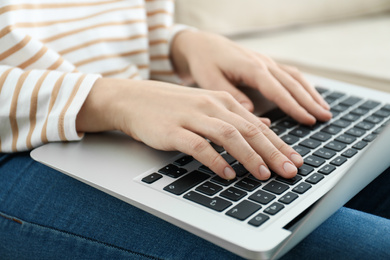 Woman working on modern laptop at home, closeup