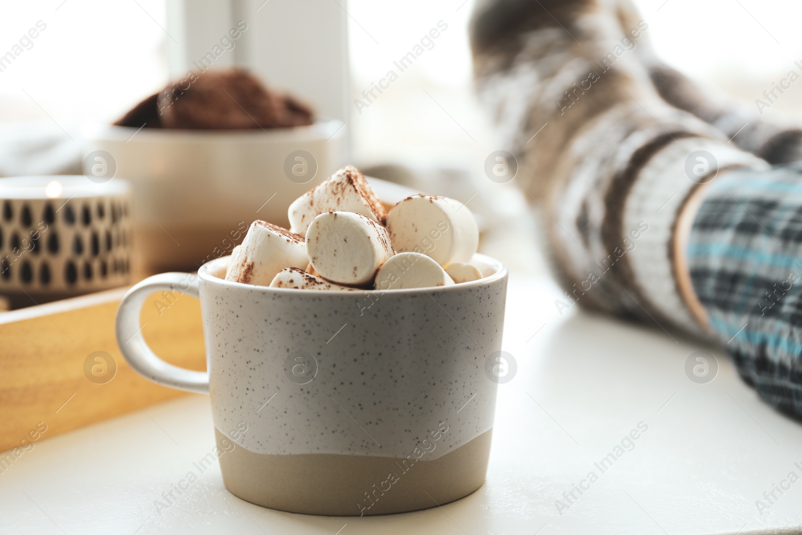 Photo of Cup of delicious hot cocoa with marshmallows near window indoors. Winter drink