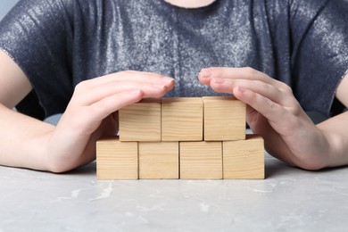 Photo of Woman demonstrating empty cubes at grey marble table, closeup. Space for design