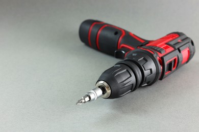Photo of Modern cordless electric screwdriver on grey background, closeup. Space for text