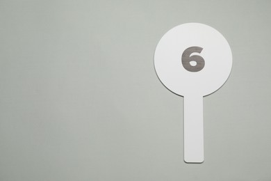 Photo of Auction paddle with number 6 on light grey background, top view. Space for text