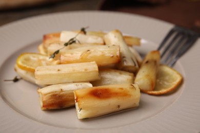 Photo of Baked salsify roots, lemon and thyme on plate, closeup
