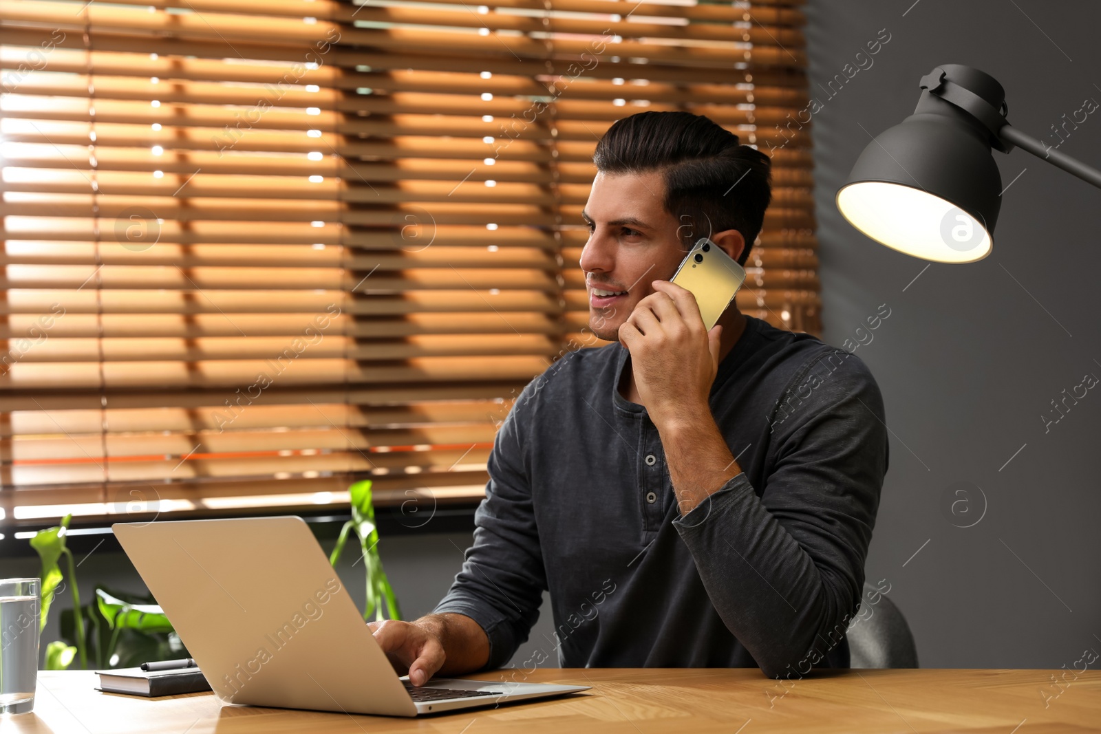 Photo of Man with modern smartphone and laptop at wooden table in office. Searching information