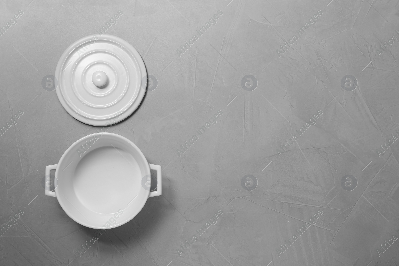 Photo of Empty ceramic pot and lid on light grey textured table, flat lay. Space for text