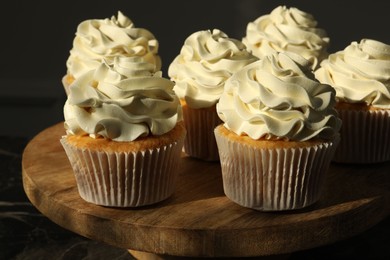 Photo of Tasty cupcakes with vanilla cream on black table, closeup