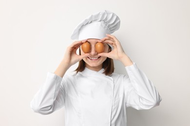 Photo of Professional chef with chicken eggs having fun on light background