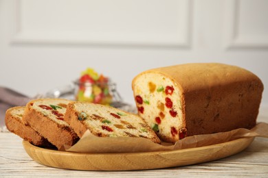 Delicious cake with candied fruits on white wooden table