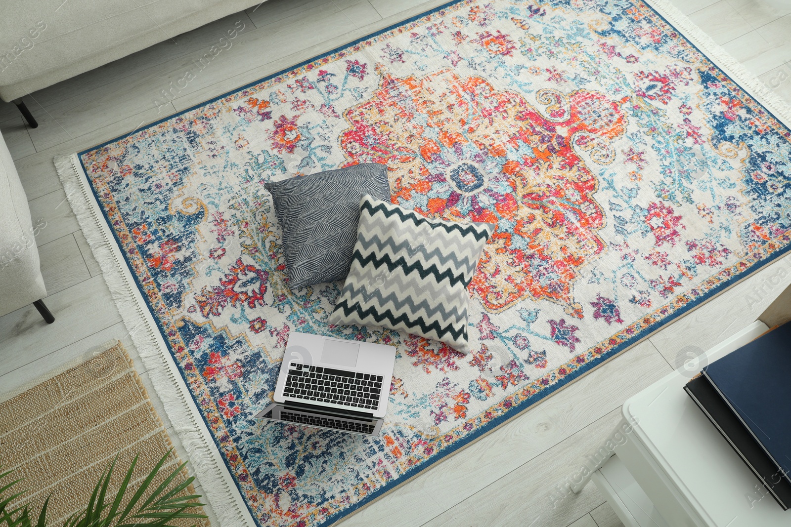 Photo of Stylish living room with beautiful carpet, laptop and pillows on floor, above view. Interior design