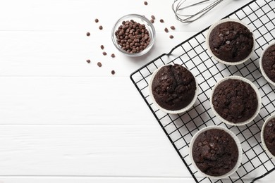 Photo of Tasty chocolate muffins on white wooden table, flat lay. Space for text