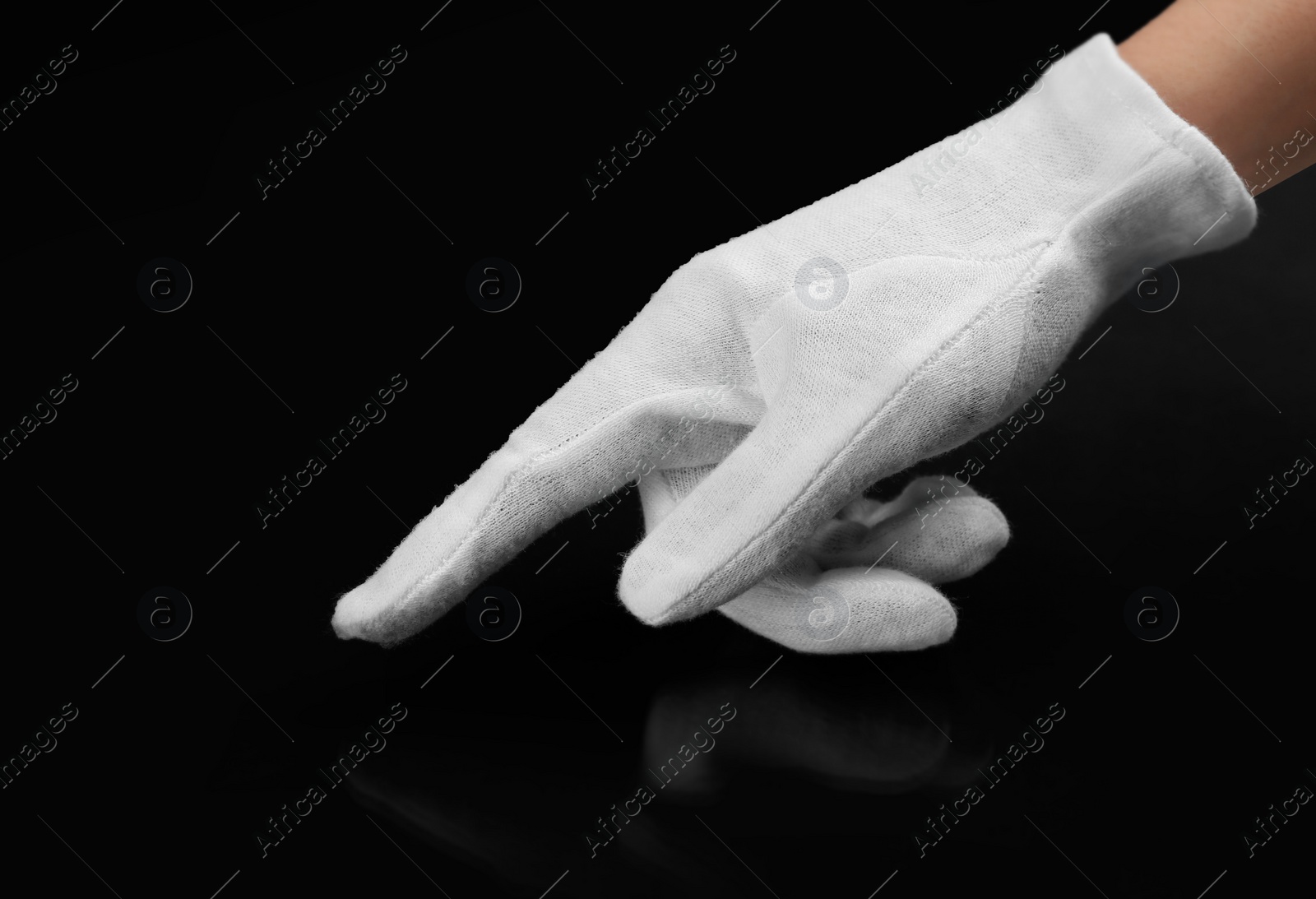 Photo of Person in white glove checking cleanliness of black background, closeup