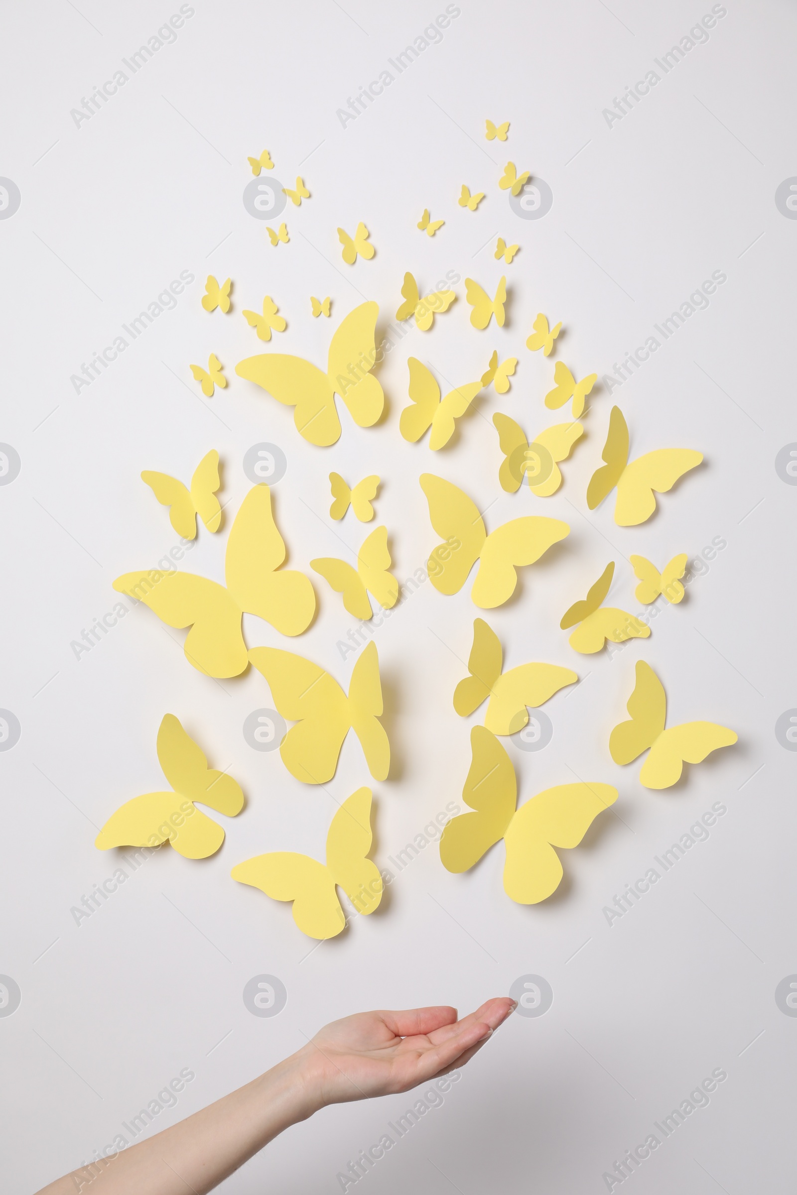 Photo of Woman with yellow paper butterflies on white background, top view