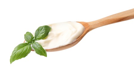 Photo of Wooden spoon with tasty mayonnaise and basil isolated on white