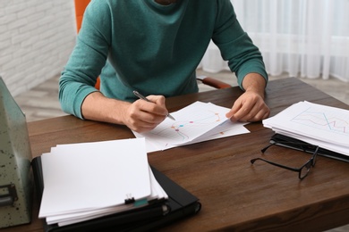 Photo of Businessman working with documents at office table, closeup