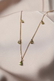 Photo of Elegant necklace on beige cloth. Stylish bijouterie