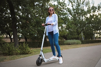 Photo of Young woman with electric kick scooter in park