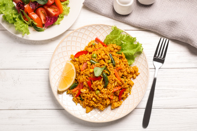 Photo of Delicious rice pilaf with vegetables on white wooden table, flat lay